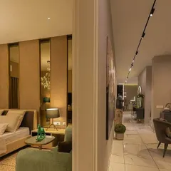 A view from the bedroom into the hallway of a luxury apartment. The lighting design uses a combination of a decorative chandelier inside the room for ambiance and a sleek magnetic track system in the corridor for functional, modern pathway lighting.