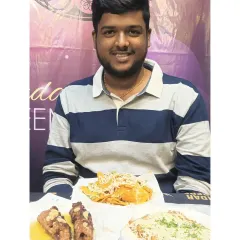 A happy guest ready to dig into a spread of our specialties, including the famous Butter Garlic Seekh and other delicious appetizers.