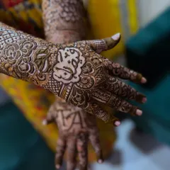 A close-up of the bride's palm, featuring the name "Akbar" written in beautiful calligraphy, surrounded by intricate floral patterns.