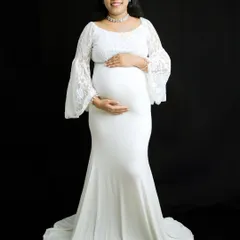 This mom-to-be looks radiant in a form-fitting white maternity gown with delicate lace sleeves. This full-length portrait against a dark backdrop highlights her beautiful silhouette and pregnancy glow.