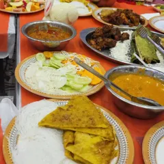 A complete meal spread featuring string hoppers (idiyappam) and folded crepes, served alongside rich curries and fried chicken.