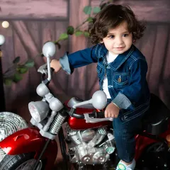 A candid moment from the rockstar photoshoot, capturing this toddler's happy expression as he sits on the toy motorcycle. I aim for natural smiles and authentic moments.