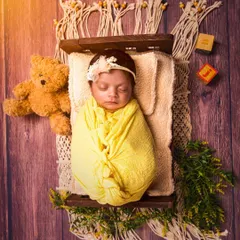 Sweet dreams in a rustic setting. This overhead shot shows a newborn sleeping on a miniature wooden bed with macrame details, creating a beautiful bohemian-inspired portrait.