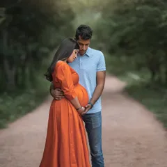 A quiet, intimate moment between a couple on a tree-lined country path. The soft, diffused light and natural framing create a dreamy, romantic atmosphere for this outdoor maternity portrait.