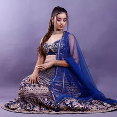 A full-length seated portrait from the same studio session. This pose elegantly displays the entire lehenga, making it suitable for both a model portfolio and a lookbook.