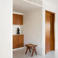 A custom-built storage cabinet in teak, nestled in an entryway. This piece provides a pause point upon entering the home, offering both concealed storage and a surface for display.