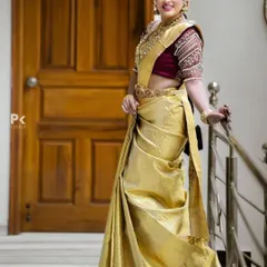 Another elegant South Indian bridal look, featuring a golden silk saree with a contrasting maroon blouse. The look is completed with a rental set of temple jewellery, including a waist belt and layered necklaces.