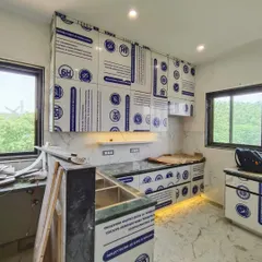This shot captures the kitchen as it comes to life. The under-cabinet lighting is on, and the marble-patterned backsplash is in place, with the cabinets awaiting their final unwrapping.