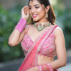 A close-up of the smiling model, her pink lehenga and green-stoned jewellery creating a fresh and joyful look.