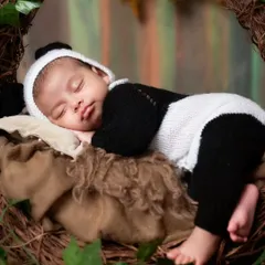 So precious! A newborn sleeps peacefully in a knitted panda costume, nestled in a rustic vine wreath.