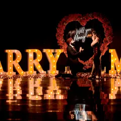 A wider angle of the "MARRY ME" setup, showing the couple's reflection on the glossy floor for an even more dramatic effect.