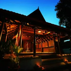 This is the historic Aranmula Palace, our reception and administration block, glowing under the twilight sky. Originally the Queen's Palace of a royal family in Kerala, this 200-year-old wooden marvel was carefully relocated and restored to welcome you into a world where royal heritage meets Ayurvedic healing.