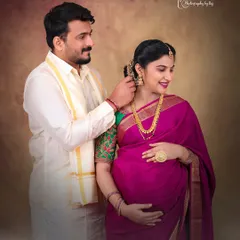An intimate moment between a couple during their traditional indoor maternity shoot. The husband-to-be lovingly places a flower in his wife's hair.