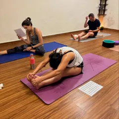 Students working on their seated forward folds, some using printed sequences for reference in a self-paced class. This posture calms the mind and stretches the entire back of the body.