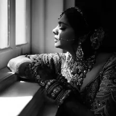 A bride caught in a moment of quiet reflection by a window. This black and white portrait uses natural light and shadow to create a timeless, soulful image.