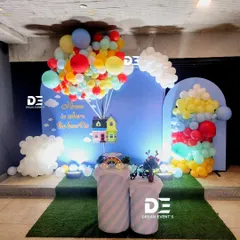 A creative and whimsical housewarming party theme inspired by the movie 'Up', featuring a colorful balloon arrangement lifting a house cutout.