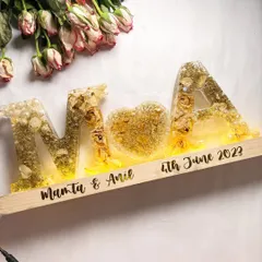 The same alphabet lamp, but with the lights turned on. The warm glow illuminates the preserved flowers, creating a magical effect.