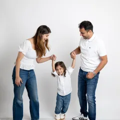 A playful family moment, with mom and dad swinging their happy son between them.