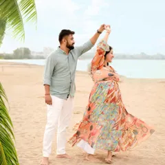 A joyful, candid moment of a couple dancing on the beach, with the colorful dress flowing in the breeze.
