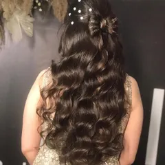 For this party look, we created a half-up hairstyle with a bow made of hair. The rest of the hair was styled in long, flowing curls and decorated with delicate pearl pins for a touch of elegance and romance.