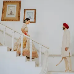 A beautifully composed "first look" moment from a Sikh wedding, as the bride descends the stairs towards her waiting groom.