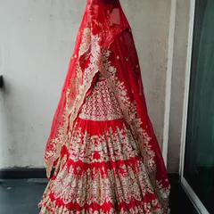 A full-length view of this magnificent tiered bridal lehenga in a classic red. The detailed gota patti work and the dramatic double dupatta created a truly regal silhouette for the bride's grand entrance.