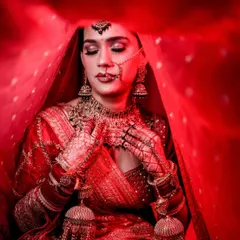 A powerful bridal portrait using a vibrant red veil to create a frame. The dramatic lighting and the bride's serene expression make this a truly artistic shot.