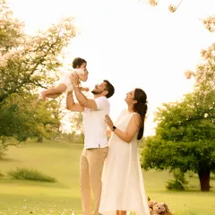 A classic, joyful family pose during an outdoor session. The father lifts the baby high in the air, creating a dynamic and heartwarming image filled with laughter and movement.