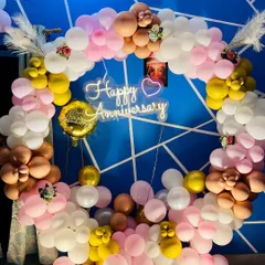A detailed close-up of the anniversary balloon arch, showing the mix of different balloon sizes and floral-style clusters. The soft lighting and pampas grass accents add an elegant touch.