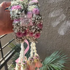 A close-up of a floral kaliree made with pink chrysanthemums, baby's breath, and hanging rosebuds. This shows the dense, textured top part of the accessory.