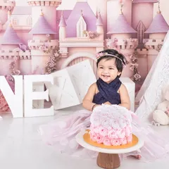 A princess cake smash for a little princess. She looks so happy with her beautiful rose cake in front of a magical castle backdrop.