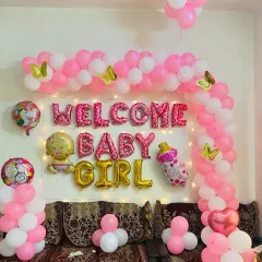 A classic and joyful "Welcome Baby Girl" decoration for a special homecoming. This arrangement includes a pink and white balloon arch, shimmering fairy lights, and charming foil balloons like a unicorn and a baby bottle to create a warm, celebratory atmosphere.