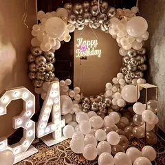 A glamorous white and silver theme for a 34th birthday. This decoration features a full balloon ring, a neon sign, and large marquee numbers, creating a luxurious and celebratory feel.