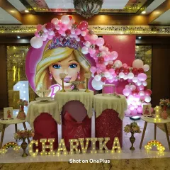 For this first birthday, I created a glamorous Barbie theme. The setup includes a large circular Barbie backdrop, a cascading pink balloon arch, and a custom light-up marquee name for the birthday girl.
