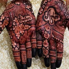A close-up of the groom's name, "Abraham," beautifully written into the bride's palm. The dark stain makes the personalized element stand out even more.