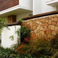Another example of a natural stone compound wall, where the irregular shapes and warm tones of the stone create a beautiful contrast with the soft foliage. This is how we build with nature, not just in it.