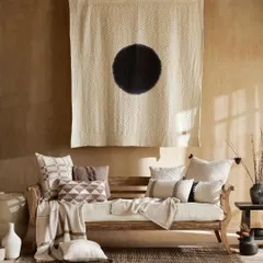 A duplicate of image 22, this shot captures a living room setting with a focus on texture and minimalist art. The natural light brings out the details in the wooden daybed, patterned cushions, and woven rug.