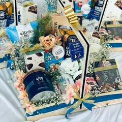 Our luxury snack hampers are designed to delight the senses. This overflowing pinewood basket is artfully arranged with a premium selection of gourmet popcorn, Nutella, cookies, and fine chocolates, adorned with fresh flowers for a truly impressive presentation.