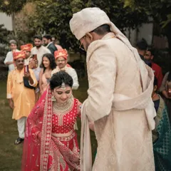 The groom leads his bride, a symbolic and beautiful moment in the wedding ceremony. The focus is on their connection amidst the crowd of loved ones.