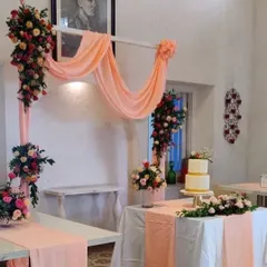 A simple and elegant setup for an intimate celebration, featuring a peach color scheme with beautiful draping and floral arrangements. This versatile design is perfect for birthdays or anniversaries.