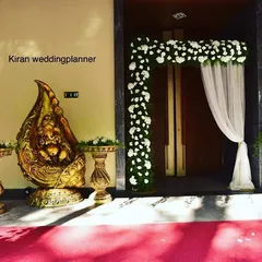 An elegant entrance for an engagement party, featuring a floral arch, sheer white drapes, and a traditional golden Ganesha idol to welcome guests.