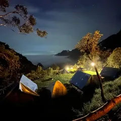 Our campsite at night, lit up under a starry sky with a river of clouds settled in the valley below. It's a surreal experience.