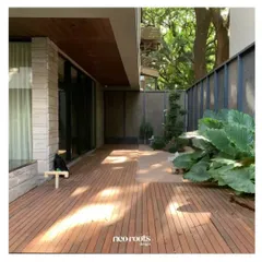 An expansive wooden deck provides a warm and inviting outdoor living space adjacent to this modern home. The clean lines of the deck are complemented by large-leafed plants, creating a contemporary yet natural feel.