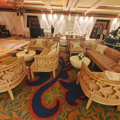 An expansive lounge area with multiple seating clusters. The unique, carved-wood sofas and armchairs are arranged to facilitate conversation, demonstrating our ability to furnish large spaces for networking events.