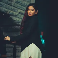A night portrait using ambient city lights to create a moody and mysterious feel. The dark tones and pop of color in the subject's hair add to the cinematic quality of the shot.
