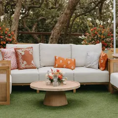 A comfortable and stylish lounge area with natural wood furniture and custom-printed cushions in shades of orange.