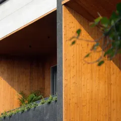 The façade of the House of Dancing Screens is an exquisite blend of contrasting materials. The warmth of the wooden louvers and terracotta screens is balanced by the cool, dark tones of the surrounding structure, adding depth and vibrancy.