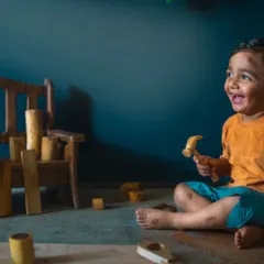The pure joy on a child's face as he plays. This studio shot captures the happiness of a fourth birthday, with wooden toys and a simple setup that lets his personality shine.