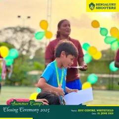 A young player's excitement is clear as he receives his medal and certificate at the summer camp closing ceremony.