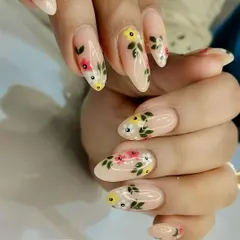 An elegant and detailed floral manicure on long, oval-shaped nails. The sheer nude base provides the perfect canvas for the meticulously hand-painted flowers and leaves, creating a sophisticated and timeless design.